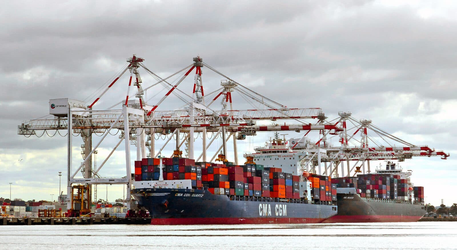 Container ship berthed at port beneath loading cranes